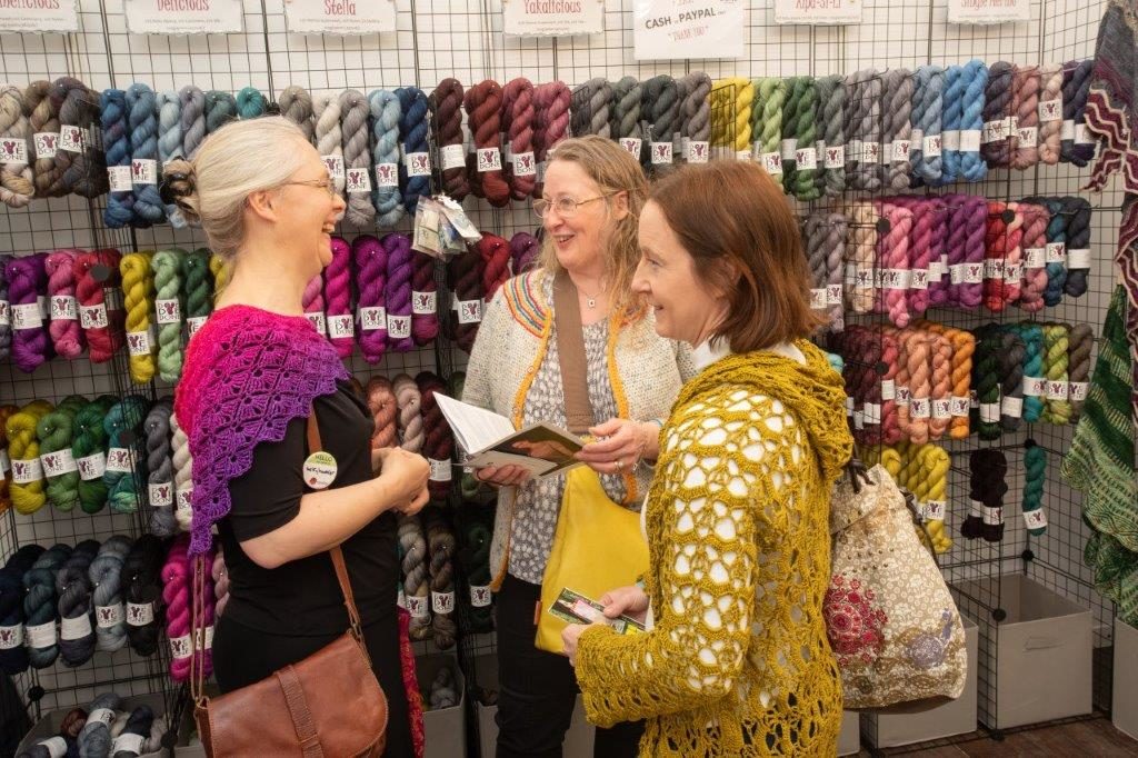 knitters in front of yarn vendor booth talking and smiling at woollinn yarn festival