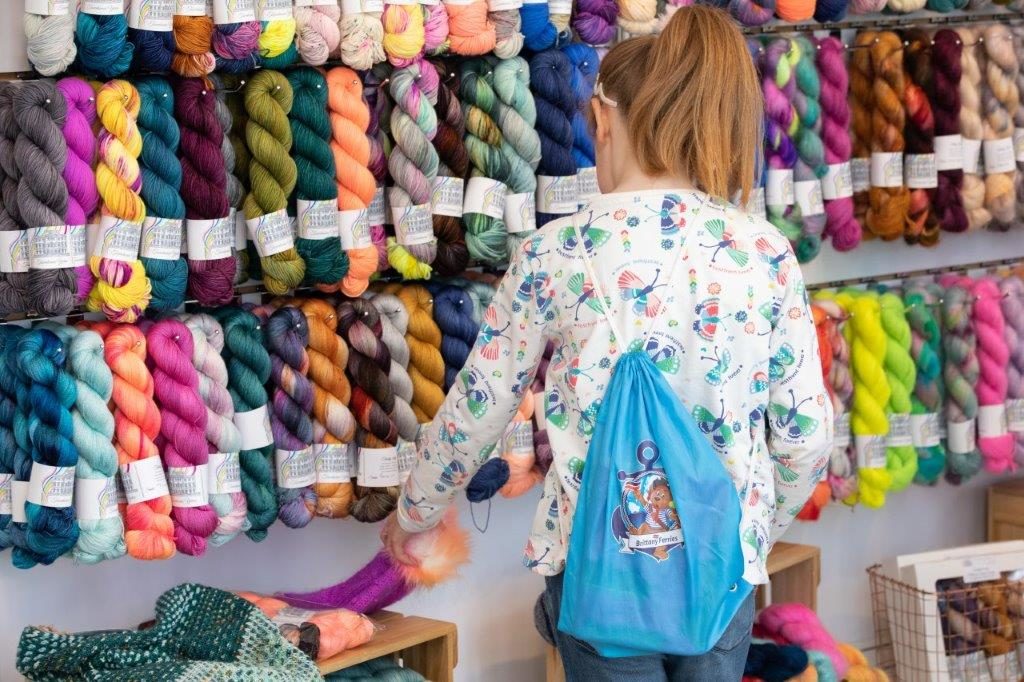 knitter browsing wall of colourful yarn at woollinn yarn festival 