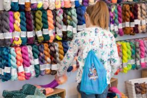 knitter browsing wall of colourful yarn at woollinn yarn festival